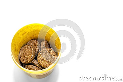 Top-Down View of Herbal Supplement Pills in a Yellow Plastic Container on White Background Stock Photo