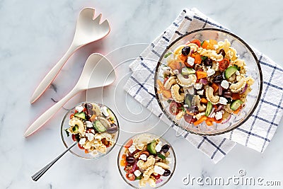 Top down view of a large Greek pasta salad with two smaller servings of the same beside. Stock Photo