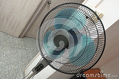 A top down wide angle view of a black floor standing electric fan with blue fan blades in a bedroom Stock Photo