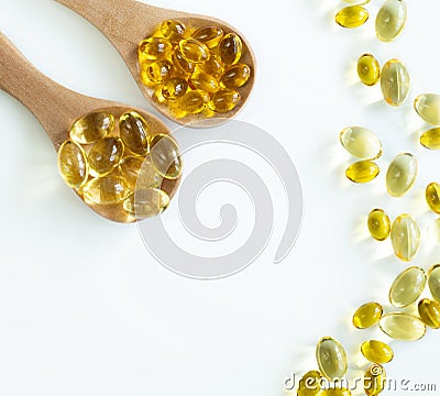 At the top of the edge there are 2 wooden spoons with capsules of omega-3 fish oil and vitamin D3 and several capsules scattered Stock Photo