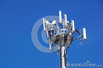 Top part of cell phone communication tower with multiple antennas against a blue sky Stock Photo