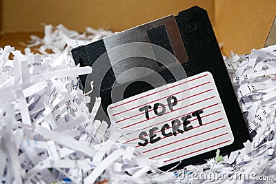 Top secret information on retro vintage floppy disk magnetic computer among shredder paper, thief information concept Stock Photo