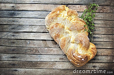 Top shot, close up of fresh baked homemade vegan braided loaf on a wooden, rustic table background, branches of thyme, home baking Stock Photo