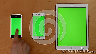 Top shot of hand touch phones and ipad on green screen. At home Top shot of hand touch phones and ipad on green screen. At home