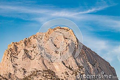 Top of stone mountain in close-up on in against blue sky Stock Photo