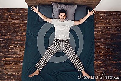 Top view. Adult cheerful man shows star, placing arms and legs aside on bed. Stock Photo