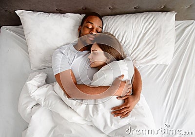 Top view of affectionate multiracial couple hugging each other while sleeping in bed Stock Photo