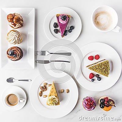 Top view of arrangement of pieces of various cakes on plates, cups of coffee and cupcakes Stock Photo