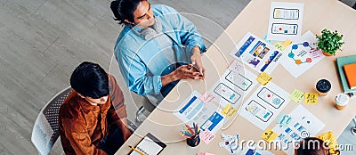 Top view asian ux developer and ui designer brainstorming about mobile app interface wireframe design on table with customer breif Stock Photo