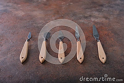 Top view and attention is focused on the beautiful wooden handles of the artistic palette knives, laid out in a row. Stock Photo