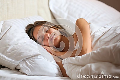 Top view of attractive young woman sleeping well in bed hugging soft white pillow. Teenage girl resting, good night sleep concept. Stock Photo