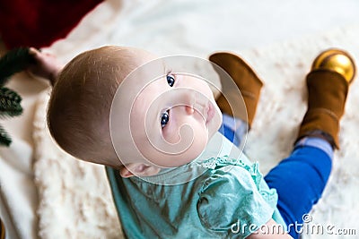 Top view baby in jeans and shoes sits near a Christmas tree, toys balls lie around Stock Photo