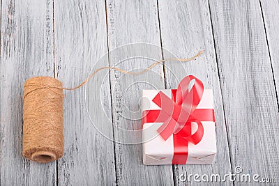 Top view on a ball of threads and a gift box on the wooden background. Stock Photo