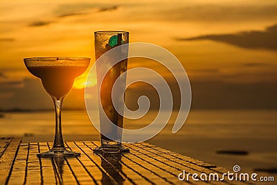 Top view bar, silhouette cocktail glasses and juice with dark cloud and sunset sky background. Stock Photo