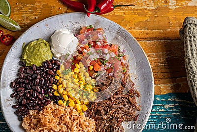 Top-view of a barbacoa burrito bowl, meat rice black beans sour cream guacamole chopped vegetables Stock Photo