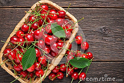 Top view basket with a harvest of ripe cherries on wooden background Stock Photo