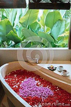 Top view of bath tub with heart shaped flower petals. Two cups of herbal tea on edge. Spa,organic and skin care, beauty treatment Stock Photo