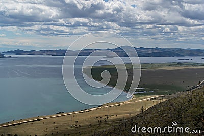 top view of the bay of lake Baikal with islands, peninsulas, clouds, mountains with green trees in sun light Stock Photo