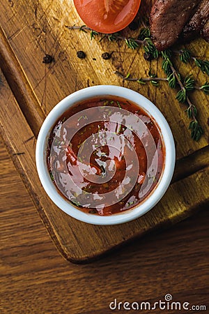 Top view of bbq sauce in bowl and delicious roasted meat with tomato Stock Photo