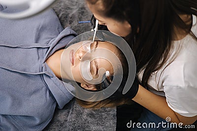Top view of beautician making eyelash lamination procedures for young blond hair model. Professional beauty studio Stock Photo