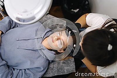 Top view of beautician making eyelash lamination procedures for young blond hair model. Professional beauty studio Stock Photo