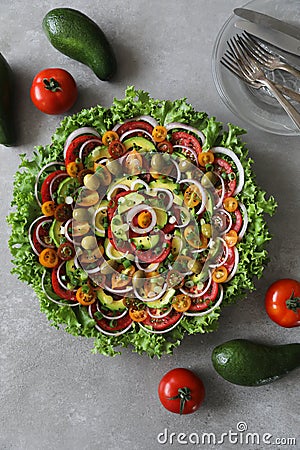 Top view of beautiful Mandala like fresh tomato, avocado, olives, lettuce and onion salad garnished with spring onion & nigella se Stock Photo