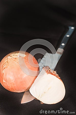 Whole and halve yellow onion with a chef`s knife`s blade Stock Photo