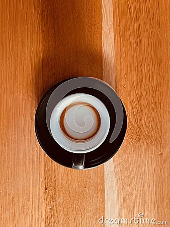 Top view of a black espresso machiatto cup on a wooden table Stock Photo