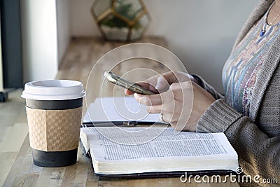Top view of Black woman studies her bible and uses phone Stock Photo
