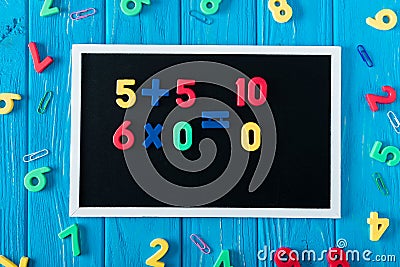 top view of blackboard with math sums colorful numbers and paper clips on blue wooden Stock Photo