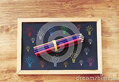 Top view of blackboard and pencils stack and various light bulbs drawing in color Stock Photo