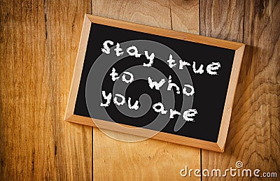 Top view of blackboard with the phrase stay true to who you are, over wooden background Stock Photo