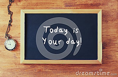 Top view of blackboard with the phrase today is your day written on it next to old clock over wooden table Stock Photo