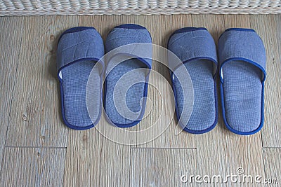 Top view blue comfortable slippers two pairs on wooden floor in the bedroom. Stock Photo