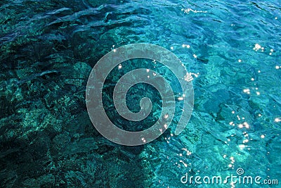 Top view of blue, green and turquoise colors of water, surface of sea on rocks and bottom. Reflection of sun beams in water. Stock Photo