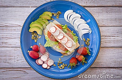 Top view of a blue plate with an healthy and dietetic sandwich with turkey meat and vegetables - healthy and tasteful eating - Stock Photo