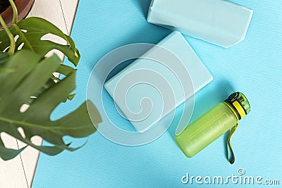 Top view of bluey yoga mat, bottle with water and yoga bricks. Stretching tools. Fitness Equipment Stock Photo