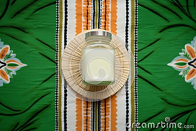 top view of body lotion in a green jar on a rattan mat Stock Photo