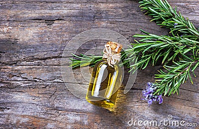Top view Bottle glass of essential rosemary oil with rosemary branch and flower on wooden rustic background Stock Photo