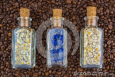 Top view of bottles of herbs on a background of freshly roasted coffee beans scattered on the table Stock Photo