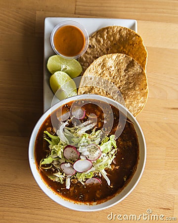 Top view of a bowl of Mexican pozole served with lime and tortilla Stock Photo