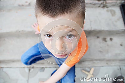 Top view boy portrait close-up sitting on stairs. Child face. Caucasian kid. fisheye effect. fish-eyed shot Stock Photo