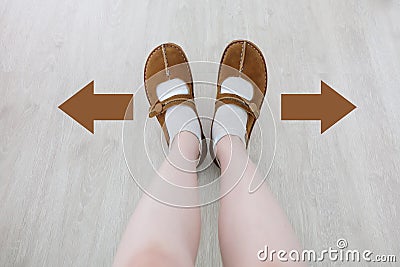 Top View of Brown Boot with Different Brown Decision Arrow. A Pair of Feet Standing. Shoes Walking Direction on Wooden Stock Photo