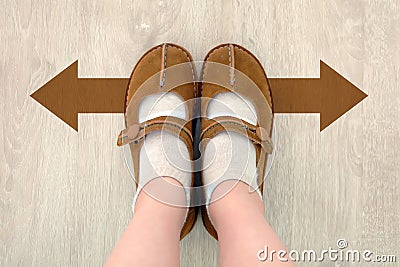 Top View of Brown Boot with Different Brown Decision Arrow. A Pair of Feet Standing. Shoes Walking Direction on Wooden Stock Photo