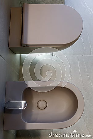 Top view of brown toilet and bidet. Modern wc interior. Gray floor and wall of the bathroom. Bottom light. Home interior design Stock Photo