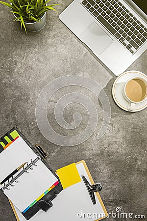 Top view of business desk with laptop, coffee, potted plant, notebook, notes paper and clipboard Stock Photo