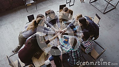 Top view of business team working at trendy loft office. Young mixed race group of people puts palm together on centre. Stock Photo