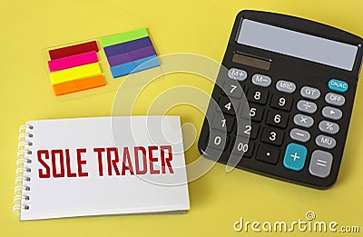 Top view of calculator, sticker and notepad with phrase SOLE TRADER isolated on yellow background. Stock Photo