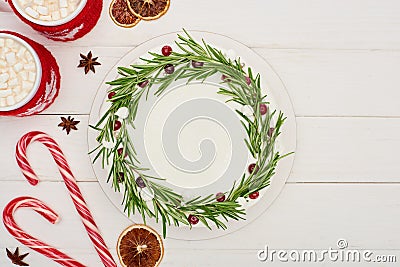 Top view of candy canes, two cups of cocoa and christmas pie with icing on white wooden table. Stock Photo