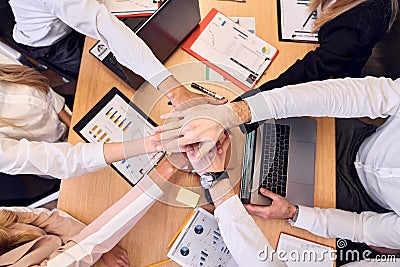 Top view of cheerful business team keeping hands together as a symbol of unity while working together in the modern office Stock Photo